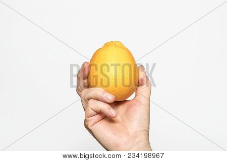 An Orange Fruit Held In One Hand