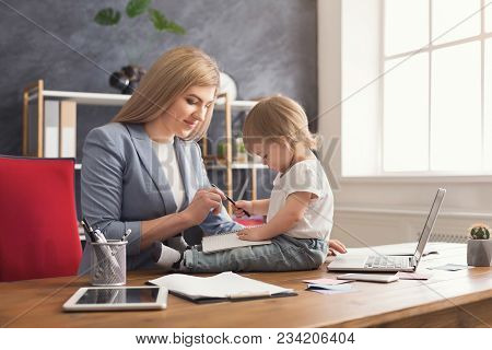 Happy Beautiful Business Mom Working On Laptop And Taking Notes While Spending Time With Her Cute Ba