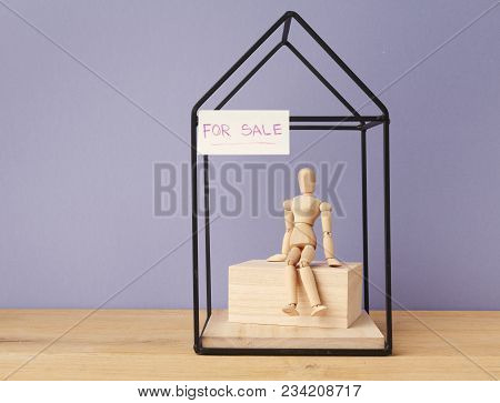 House For Sale On Purple Background. Mannequin Sitting In House. Sale, Rent From Owner Concept, Copy
