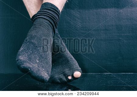 Legs Bankrupt In Black Holey Socks On A Black Background.