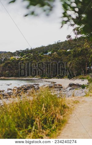 Deserted Beach In Hobart, Tasmania With Rocks And Walkpath In The Foreground On An Overcast Day With