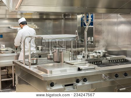 Chef Preparing Food In Commercial Stainless Steel Kitchen In Restaurant
