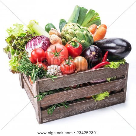 Fresh multi-colored vegetables in wooden crate. Organic food. White background.