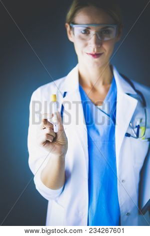 Female medical or research scientist or doctor using looking at a test tube of clear solution in a lab or laboratory.