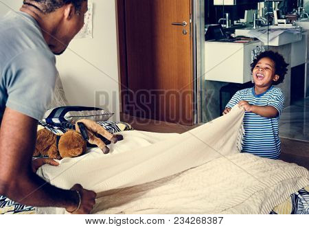 Dad and son changing bed sheet together