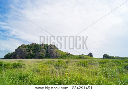 The Far Eastern Landscape Of The Krabbe Peninsula. Rocks Rise In The Field Against The Blue Sky