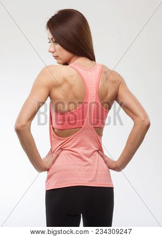Happy Young Woman In Sports Clothing. Muscular Fitness Model On White Background. Back View.