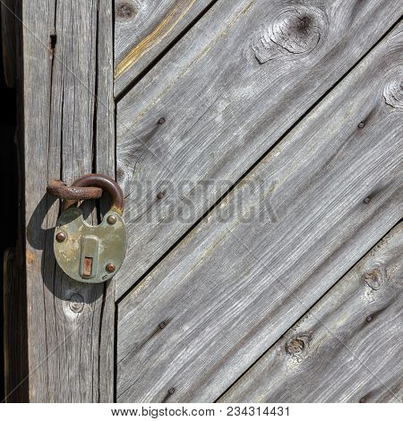 Natural wood textured background. Fragment of aged boarded door with padlock.