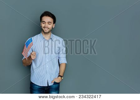 Us Citizen. Handsome Cheerful Young Man Smiling And Looking At The Us Flag While Feeling Patriotic