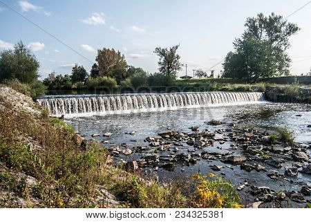 Weir On Olse River With Trees Around And Blue Sky With Clouds In Karvina City In Czech Republic