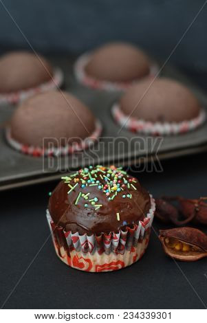 Just Baked Homebaked Chocolate Muffins For Dessert With Colored Conffeti. Black Background.