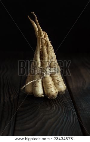 A Bunch Of Parsley Root On A Dark Wooden Table