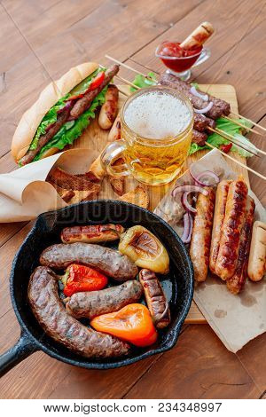 Oktoberfest. Assorted Different Grilled Sausages On A Wooden Table. Fried Sausages On A Cast-iron Fr