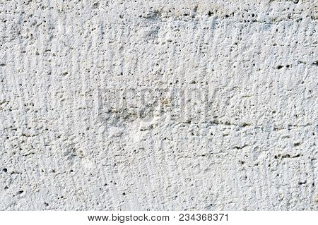Close-up Deep Texture Of White-painted Porous Stone On The Facade Of The Building. Stoned Wall Backg