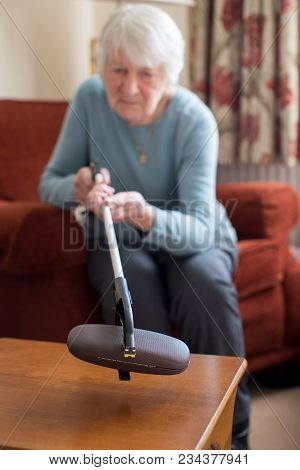 Senior Woman Using Reaching Arm To Pick Up Spectacles Case At Home