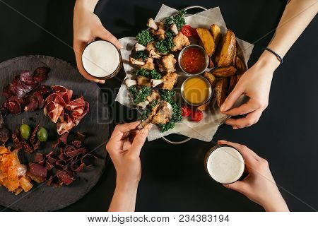 Cropped Shot Of People Drinking Beer And Eating Delicious Baked Potatoes With Roasted Chicken On Bla