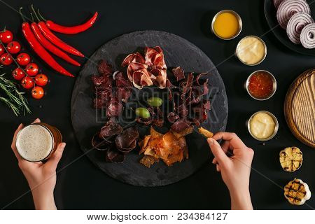 Cropped Shot Of Person Eating Gourmet Craft Meat And Drinking Beer On Black