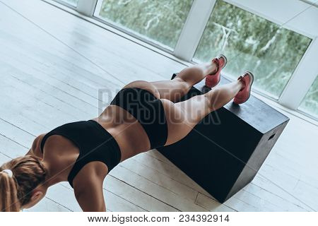 Working Hard To Be The Best. Top View Of Young Woman In Sport Clothing Keeping Plank Position While 