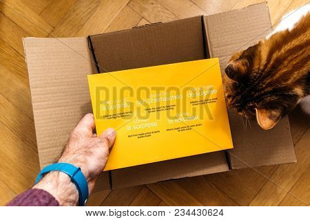 Paris, France - Feb 14, 2018: Man Unboxing Amazon.com Cardboard Containing A Surprise Yellow Envelop