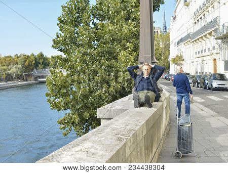 Paris, France - October 16, 2016: Man Sits And Rests On A Small Wall Near The River Sena. Paris, Fra