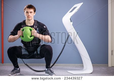 Fit Man In Electric Muscular Suit To Stimulate With Training Medecine Ball