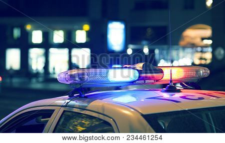 Blue Light Flasher Atop Of A Police Car. City Lights On The Background.
