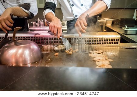 Hand Of Chef Cooking Beef Steak On Hot Pan In Front Of Customers. Tepanyaki Steak