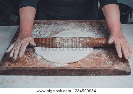 An Old Grandmother Cleansing A Dough With A Shaft On A Dark Background 2018