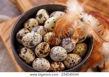 Quail Eggs In A Black Cup Close-up. A Lot Of Quail Eggs In A Cup. Quail Eggs And Feathers.