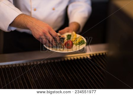 Master chef hands cooking grilled salmon fish with potatoes on a restaurant kitchen