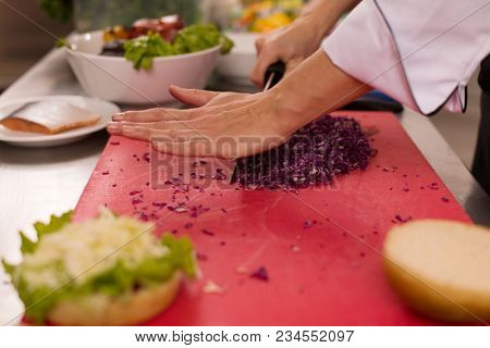 master chef cutting salad for a burger in the rastaurant kitchen
