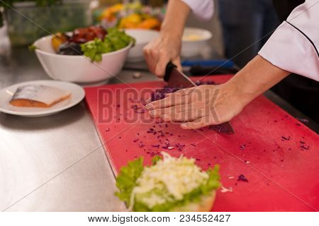 master chef cutting salad for a burger in the rastaurant kitchen
