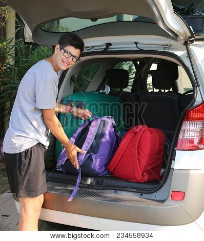 Young Boy Loads The Car For A Long Journey