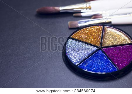 A Palette Of Colorful Glitter Eyeshadow And Profeccional Make Up Brushes On A Black Background, Clos