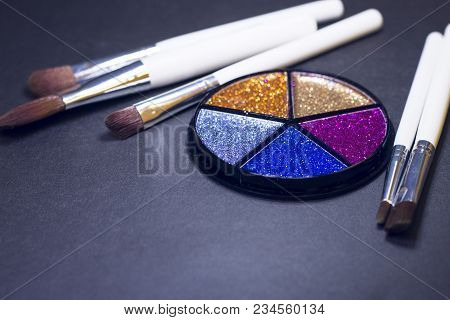 A Palette Of Colorful Glitter Eyeshadow And Profeccional Make Up Brushes On A Black Background, Clos