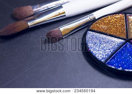 A Palette Of Colorful Glitter Eyeshadow And Profeccional Make Up Brushes On A Black Background, Clos