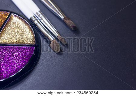 A Palette Of Colorful Glitter Eyeshadow And Profeccional Make Up Brushes On A Black Background, Clos
