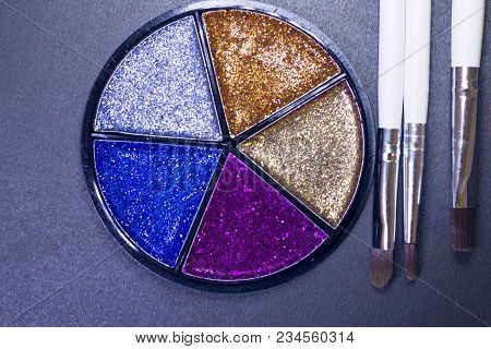 A Palette Of Colorful Glitter Eyeshadow And Profeccional Make Up Brushes On A Black Background, Clos