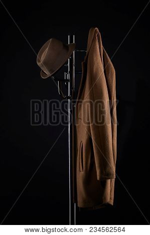 Hat And Classic Jacket Hanging On Coat Rack Isolated On Black