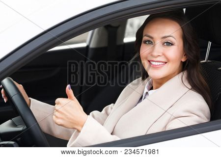 Beautiful woman driver smiling and giving thumb up inside her car