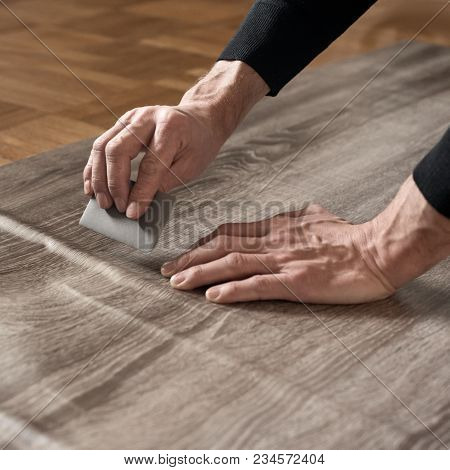 Closeup Of Carpenters Hands Removing Air From Self-adhesive Film