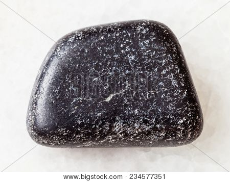 Macro Shooting Of Natural Mineral Rock Specimen - Tumbled Chromite Stone On White Marble Background 