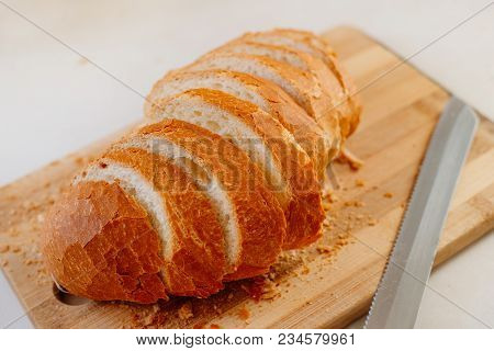 A Fresh Loaf Cut Into Pieces Lies On A Wooden Board, Next To A Knife-file For Bread. The Crust Crumb