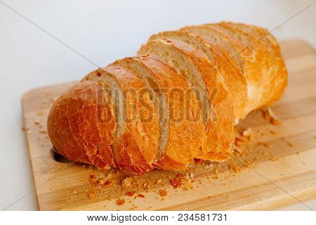 A Fresh Loaf Cut Into Pieces Lies On A Wooden Board, Next To A Knife-file For Bread. The Crust Crumb