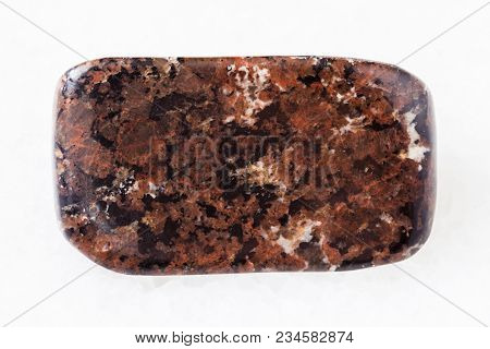 Macro Shooting Of Natural Mineral Rock Specimen - Tumbled Spreusteined Urtite Stone On White Marble 
