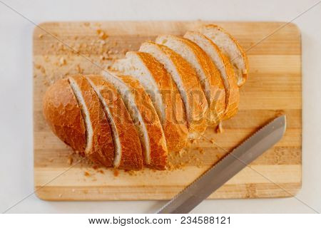 A Fresh Loaf Cut Into Pieces Lies On A Wooden Board, Next To A Knife-file For Bread. The Crust Crumb