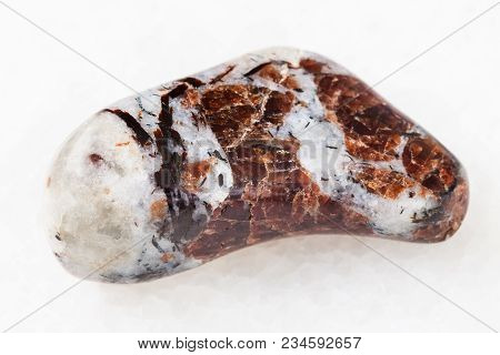 Macro Shooting Of Natural Mineral Rock Specimen - Tumbled Eudialyte In Syenite Stone On White Marble