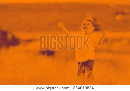 happy young beautiful child have fun on eadow with soap bubbles toy duo tone