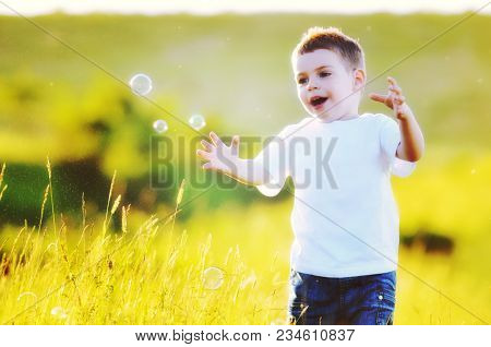 happy young beautiful child have fun on eadow with soap bubbles toy