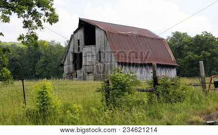 Old Barn In Green Field With Trees